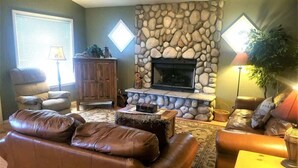 Una sala de estar con chimenea de piedra, sofás de cuero, un aparador de madera y una lámpara.