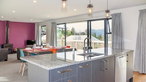 A modern kitchen with a granite countertop, stainless steel appliances, and a large window offering a view of the outdoors. - Lofty Quarters - Hamner Springs Holiday Home (Hanmer Springs)