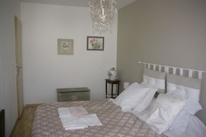 A bedroom with a bed, a dresser, a nightstand, a chandelier, and two framed pictures on the wall. - Les petits déjeuners de flo (Nozay)
