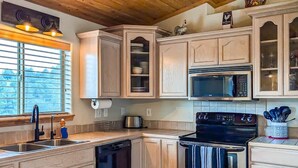 A kitchen with a built-in oven, microwave, and a large window with blinds. - Spacious Mountain-Views with Game Room + Fireplace (Alto)