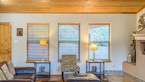 A cozy living room with a wooden ceiling, a leather sofa, a patterned armchair, and a small table with a lamp. - Spacious Mountain-Views with Game Room + Fireplace (Alto)