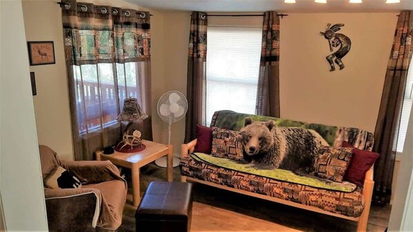 Una sala acogedora con un sofá estampado, una mesita y un ventilador.
