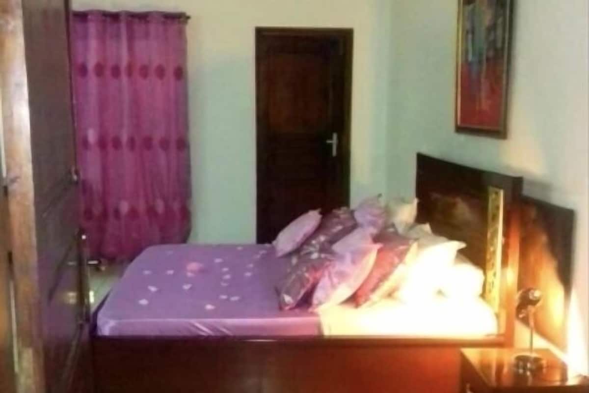 Ein Schlafzimmer mit Bett, einer Tür, einer Wand mit Gemälde und einem Fliesenboden.