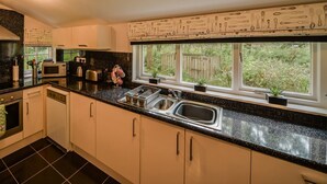 Eine moderne Küche mit schwarzen Granit Arbeitsplatten, Edelstahlgeräten und einem Fenster mit Blick auf Grünflächen.