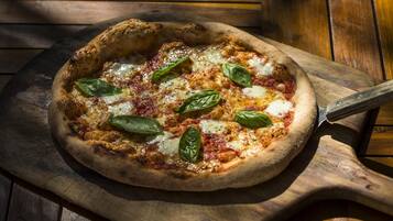 A pizza on a wooden board with a pizza cutter.