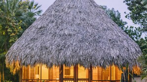 A thatched-roof hut with a wooden door and steps leading up to it, surrounded by greenery. - Turtle Inn by Francis Ford Coppola (Placencia)