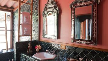 Un baño con tocador, dos espejos, lavabo y una estatua decorativa de Buda.