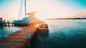 A wooden pier extending into calm waters with a sailboat docked at the end. - Turtle Inn by Francis Ford Coppola (Placencia)