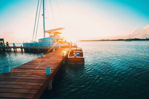 Un muelle de madera se adentra en aguas tranquilas, con un velero amarrado al final.