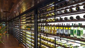 Una bodega con estantes llenos de botellas de vino, piso de madera y estanterías metálicas.