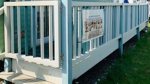 A small, light blue building with a white fence and a sign advertising a 6.8 berth caravan hire. - Golden Sands Caravan Hire (Skegness)