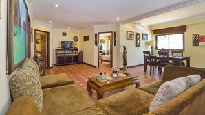 A living room with sofas, a coffee table, and a TV. There is a dining area with a table and chairs. The room has a tiled floor and a door leading to another room. - VIEWBOR VILLA - PATTAYA HOLIDAY HOUSE - WALKING STREET (Muang Pattaya)
