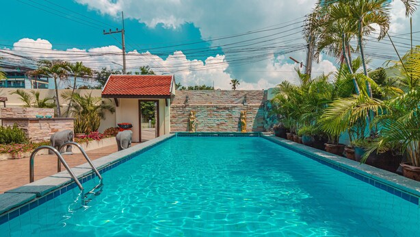 A swimming pool with clear blue water, surrounded by potted plants and a stone wall with statues. - VIEWBOR VILLA - PATTAYA HOLIDAY HOUSE - WALKING STREET (Muang Pattaya)