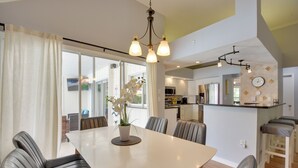 A modern dining area with a white table, black chairs, and a potted orchid.