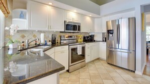 A modern kitchen with white cabinets, stainless steel appliances, and a granite countertop.