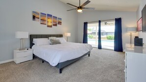 A bedroom with a bed, nightstands, a ceiling fan, and artwork on the wall.