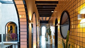 A corridor with tiled walls, wooden beams, and potted plants. - Casa Hoyos (San Miguel de Allende)