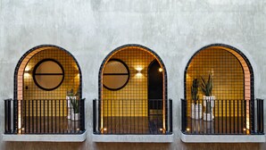A building facade with three arched windows, each with a circular design and a black railing. - Casa Hoyos (San Miguel de Allende)