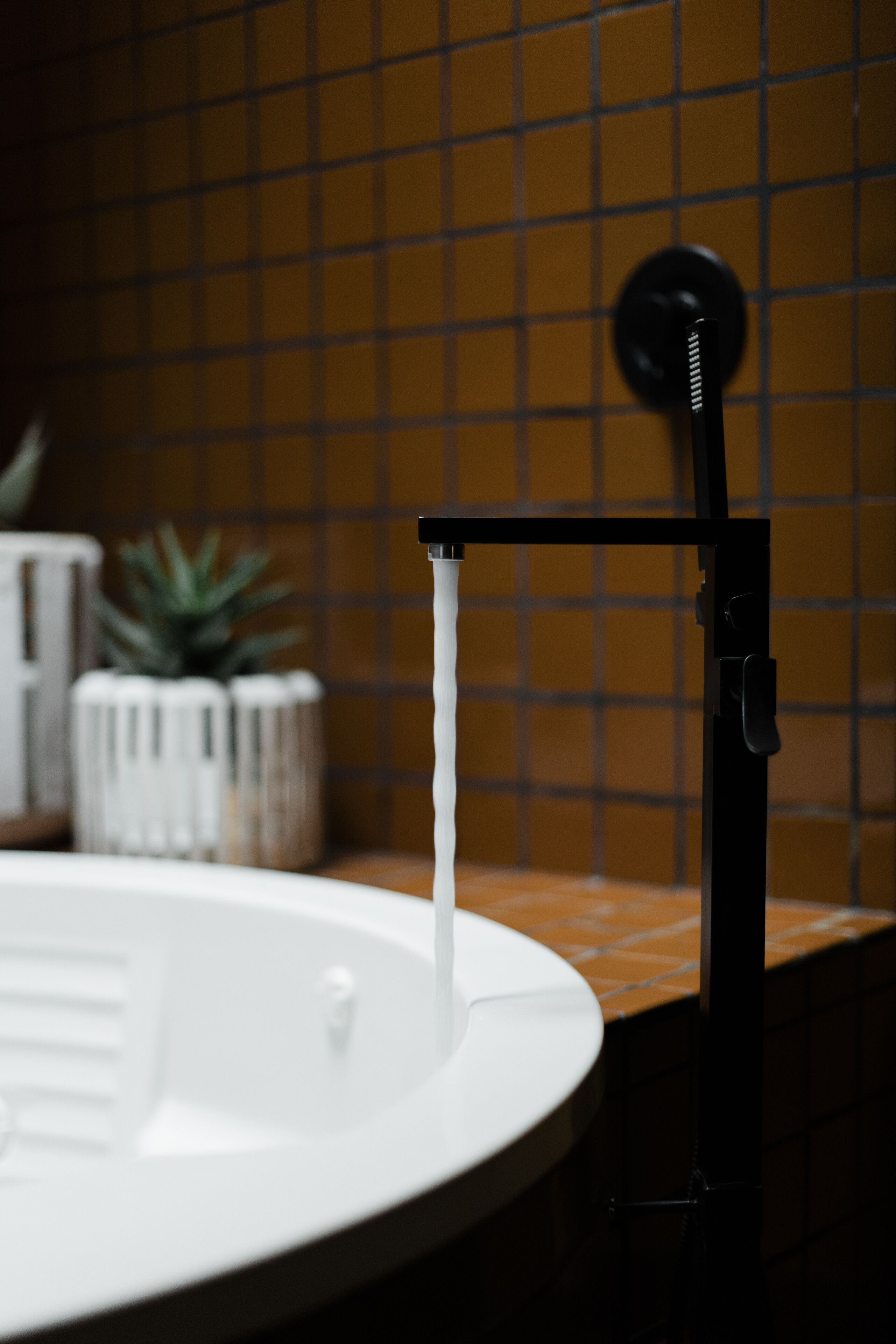 Un baño con un lavamanos blanco y un grifo negro.