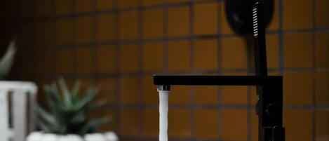 Un baño con un lavamanos blanco y un grifo negro.