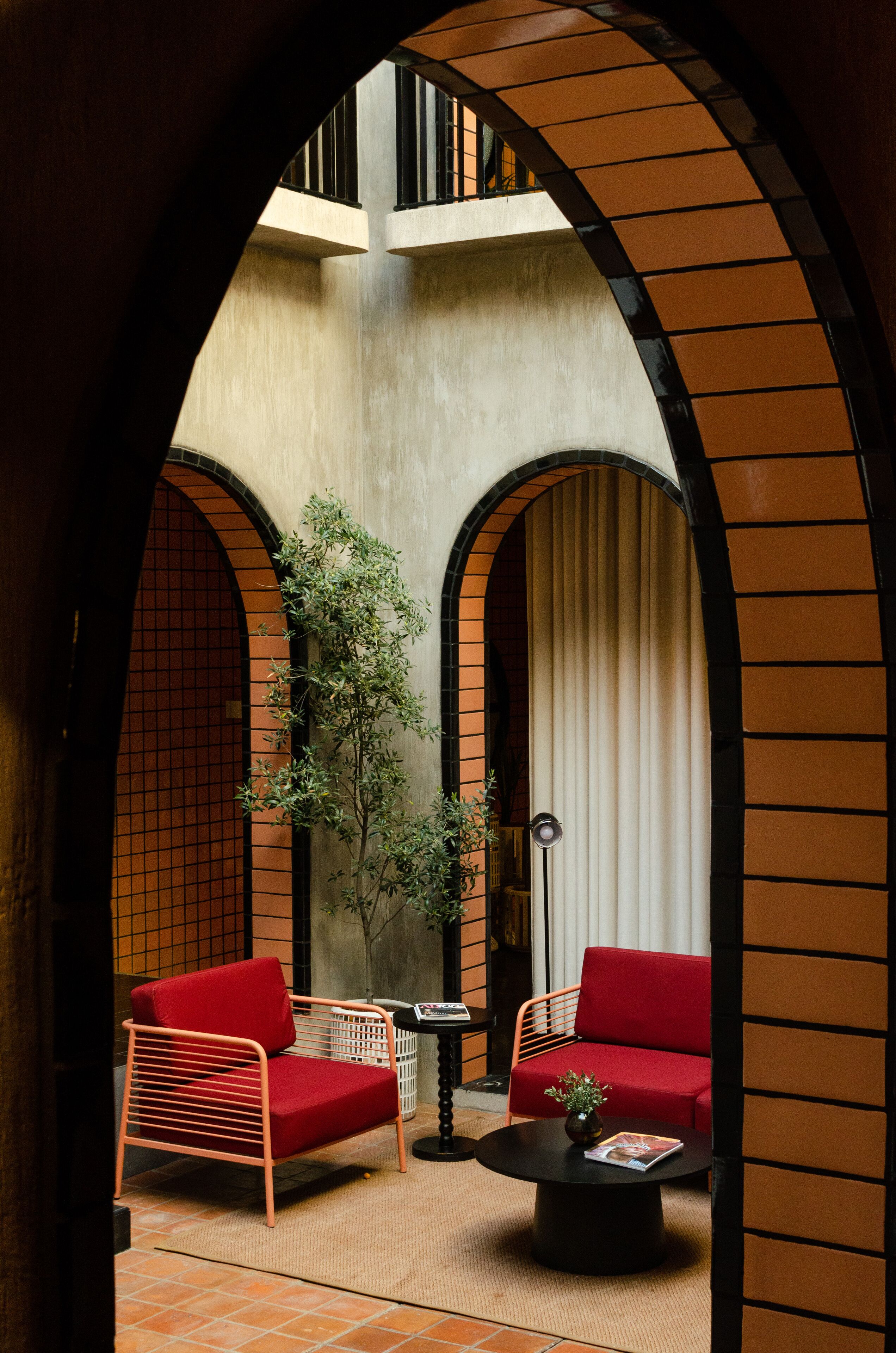 Ein Innenhof mit zwei roten Stühlen, einem schwarzen Couchtisch und einem Blumentopf.