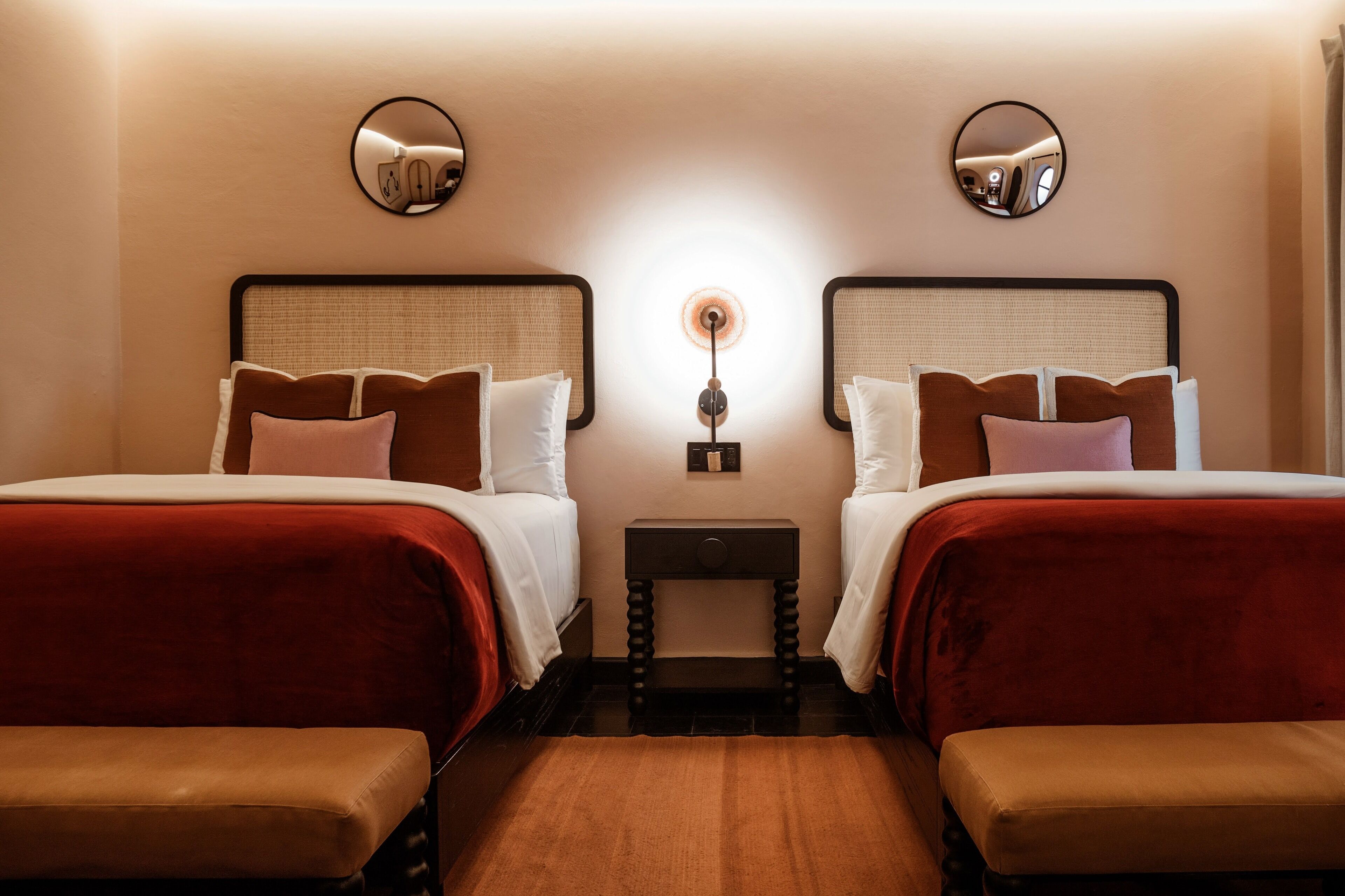 Une chambre d’hôtel avec deux lits, une petite table de chevet et un miroir au mur.