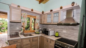 Una cocina compacta con armarios de madera, una campana extractora de acero inoxidable, un microondas, un hervidor y un lavamanos.