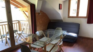 Una habitación con una mesa de vidrio y sillas, un sofá y una puerta corrediza de vidrio que da a un espacio al aire libre.