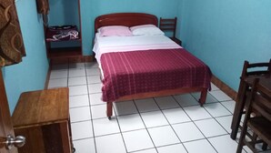 Une chambre à coucher comprenant un lit, une chaise, une armoire et un sol carrelé.