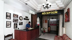 Een receptiegedeelte met een receptiebalie, een bank en een muur met ingelijste foto's.