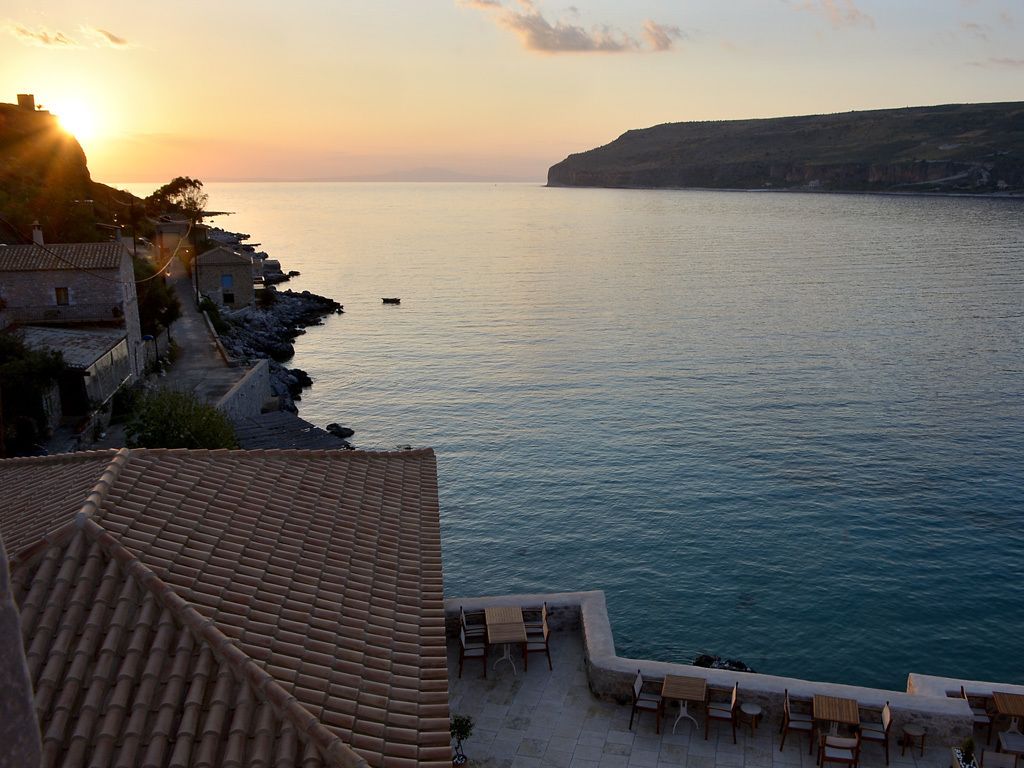 A coastal view with a terrace overlooking the sea, featuring a stone pathway and seating area.