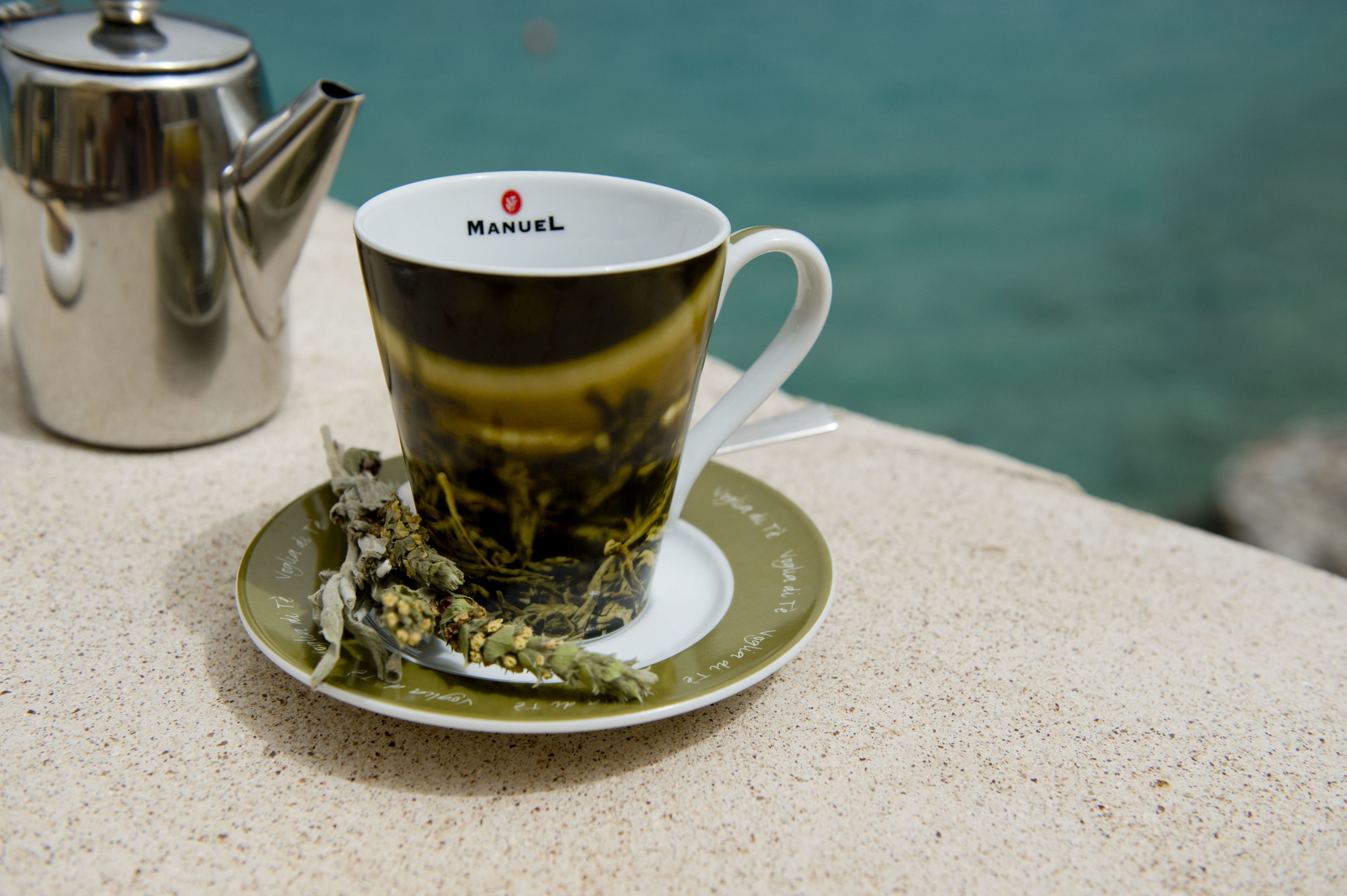 Una taza de té con tetera y platillo sobre una mesa.