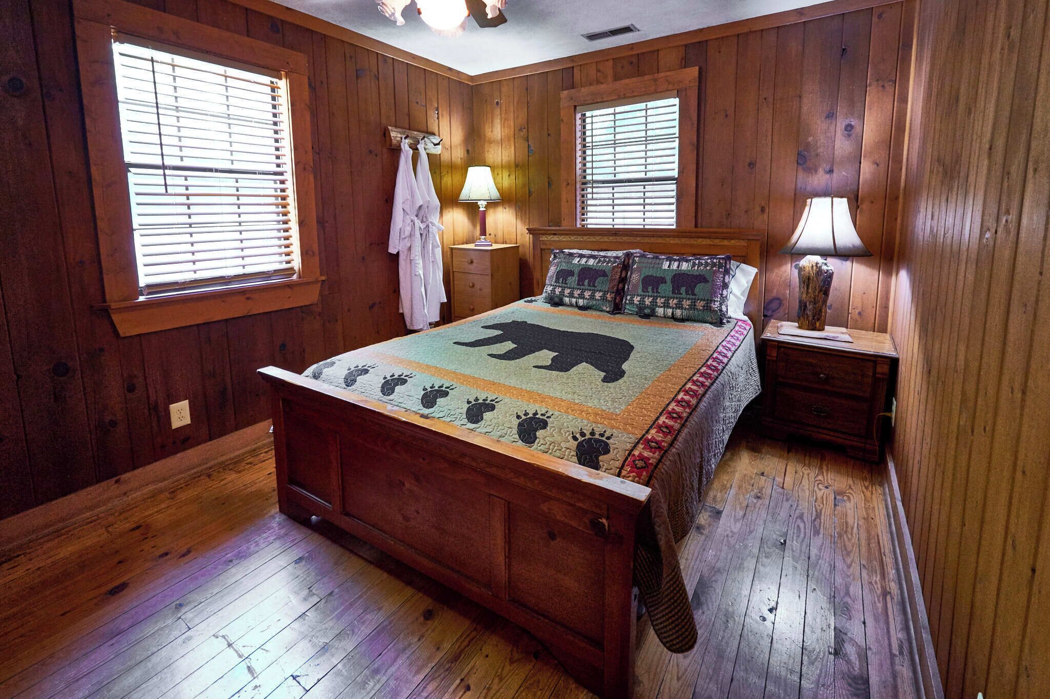 Un dormitorio con paneles de madera, una cama, dos mesitas de noche y una ventana con persianas.