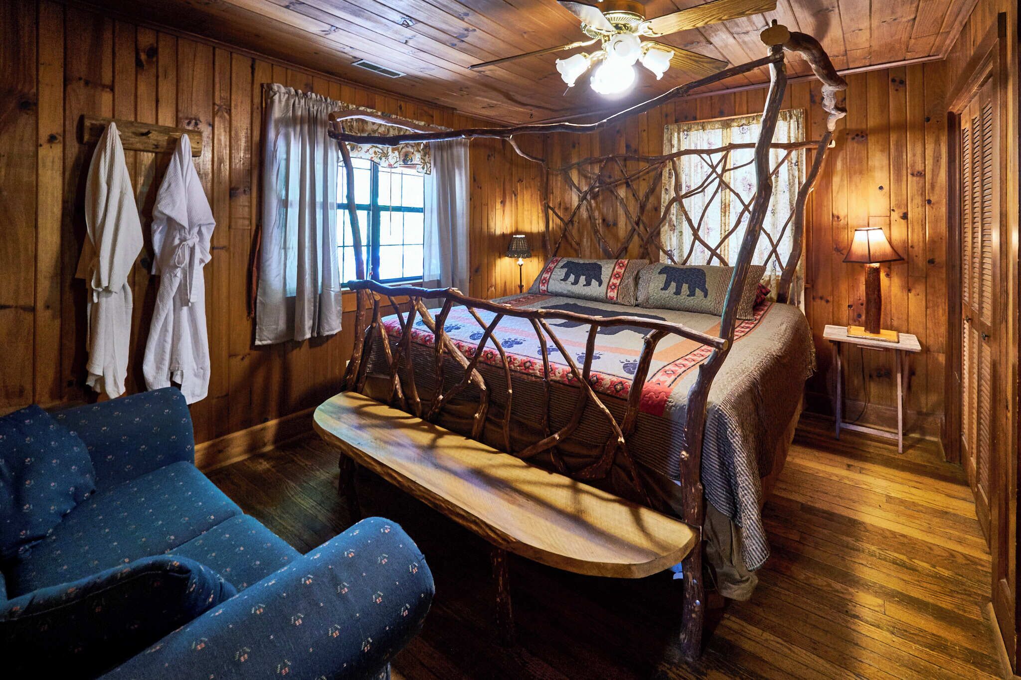 A rustic wooden room with a bed, a blue sofa, and a bench.