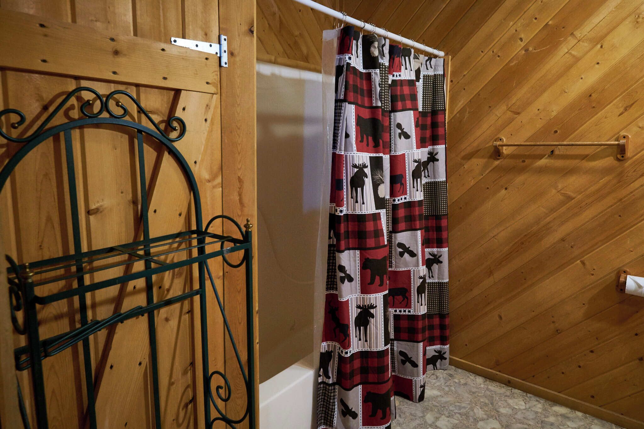 Un intérieur en bois avec une étagère en métal, un rideau à motifs et une porte en bois.