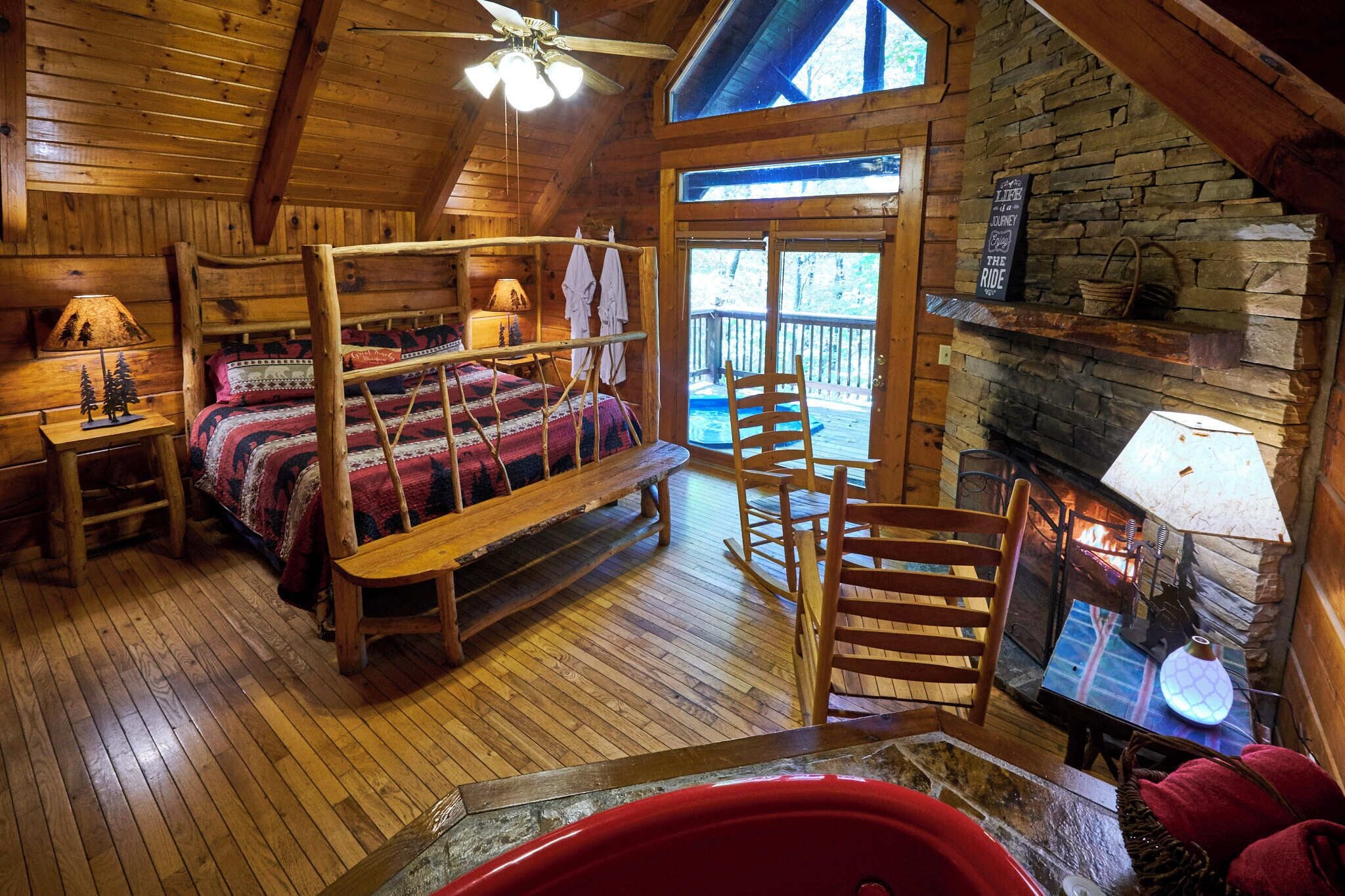 Una cabaña acogedora con interior de madera, una cama con dosel, una chimenea y un balcón con pared de piedra.