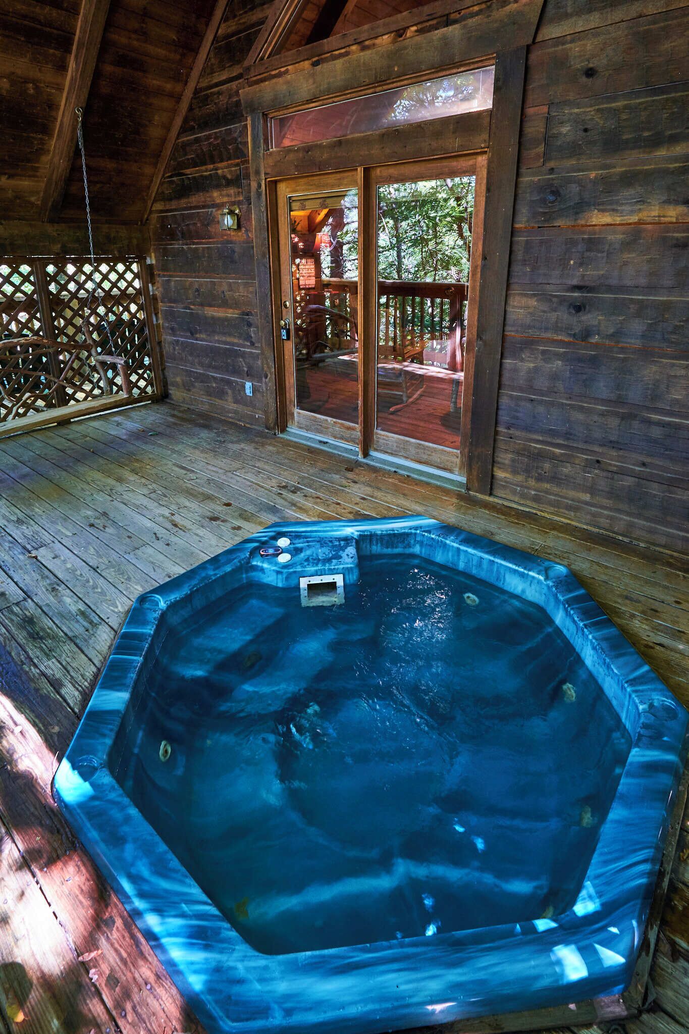 Una cabaña de madera con un jacuzzi en el porche.