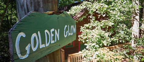 A wooden sign with the text "GOLDEN GLOW" in white letters, attached to a wooden post.