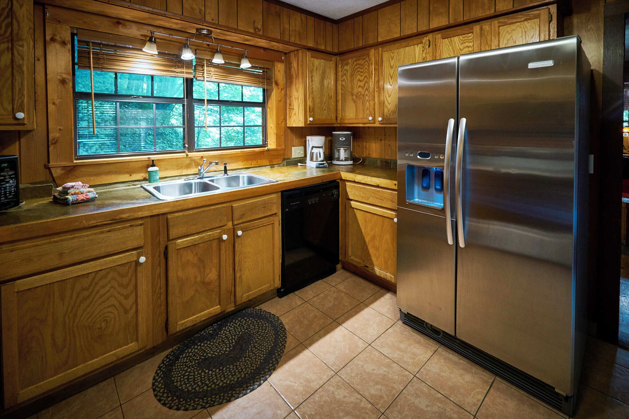 A kitchen with wooden cabinets, a stainless steel refrigerator, a coffee maker, and a dishwasher.