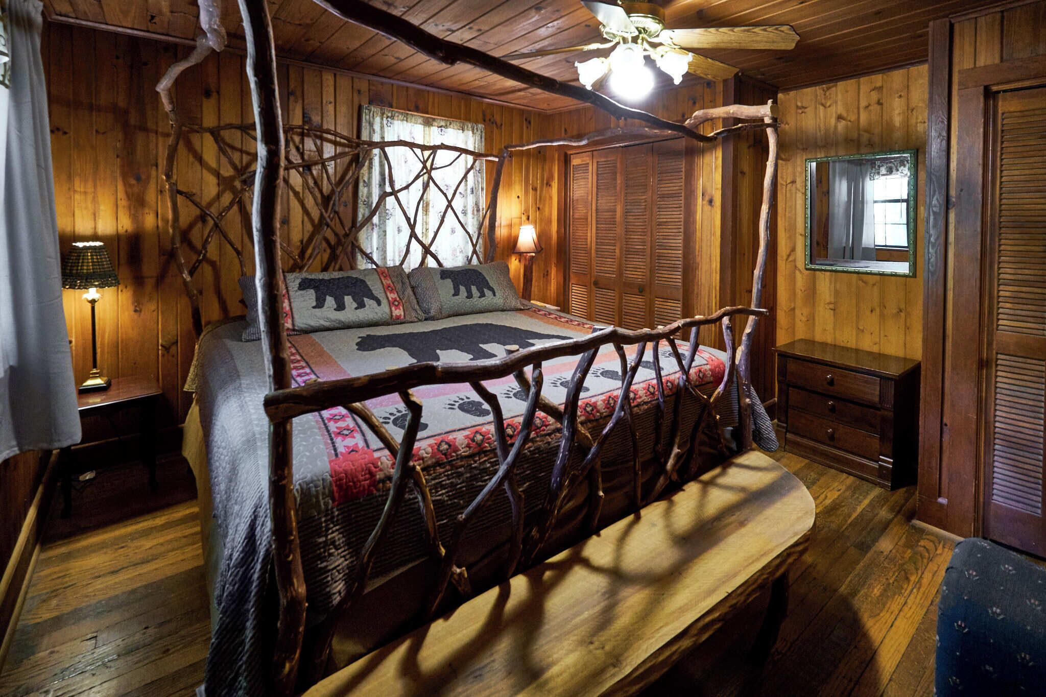 Una habitación rústica de madera con una cama con dosel, paredes de madera y un ventilador de techo.