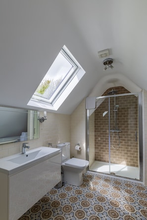 A modern bathroom with a skylight, a shower enclosure, and patterned floor tiles.