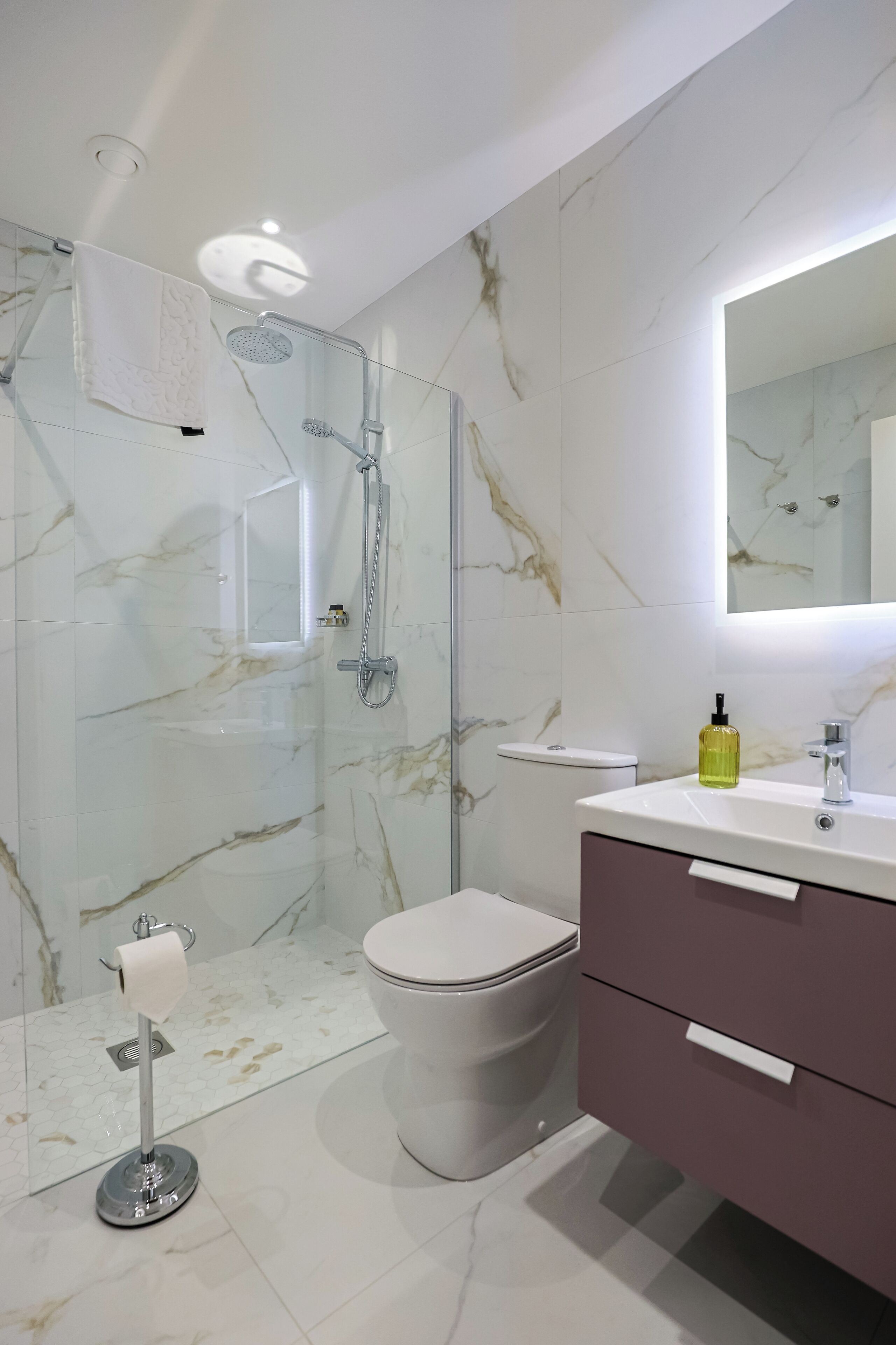 A modern bathroom with a glass-enclosed shower, a white toilet, and a vanity with a mirror.