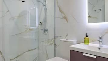 A modern bathroom with a glass-enclosed shower, a white toilet, and a vanity with a mirror.