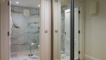 Un baño moderno con pared de mármol, inodoro y zona de ducha.