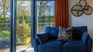 Una sala de estar moderna con un sofá azul, ventanas amplias y vistas al exterior.