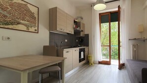 A compact kitchen with a dining area, a small oven, and a view through a glass door to an outdoor balcony. - Il Giglio Guest House (Florence)