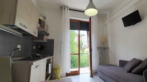 A modern kitchen with a built-in stove, cabinets, and a window with curtains. - Il Giglio Guest House (Florence)