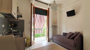 A compact living space with a kitchenette, a sofa, and a TV. - Il Giglio Guest House (Florence)