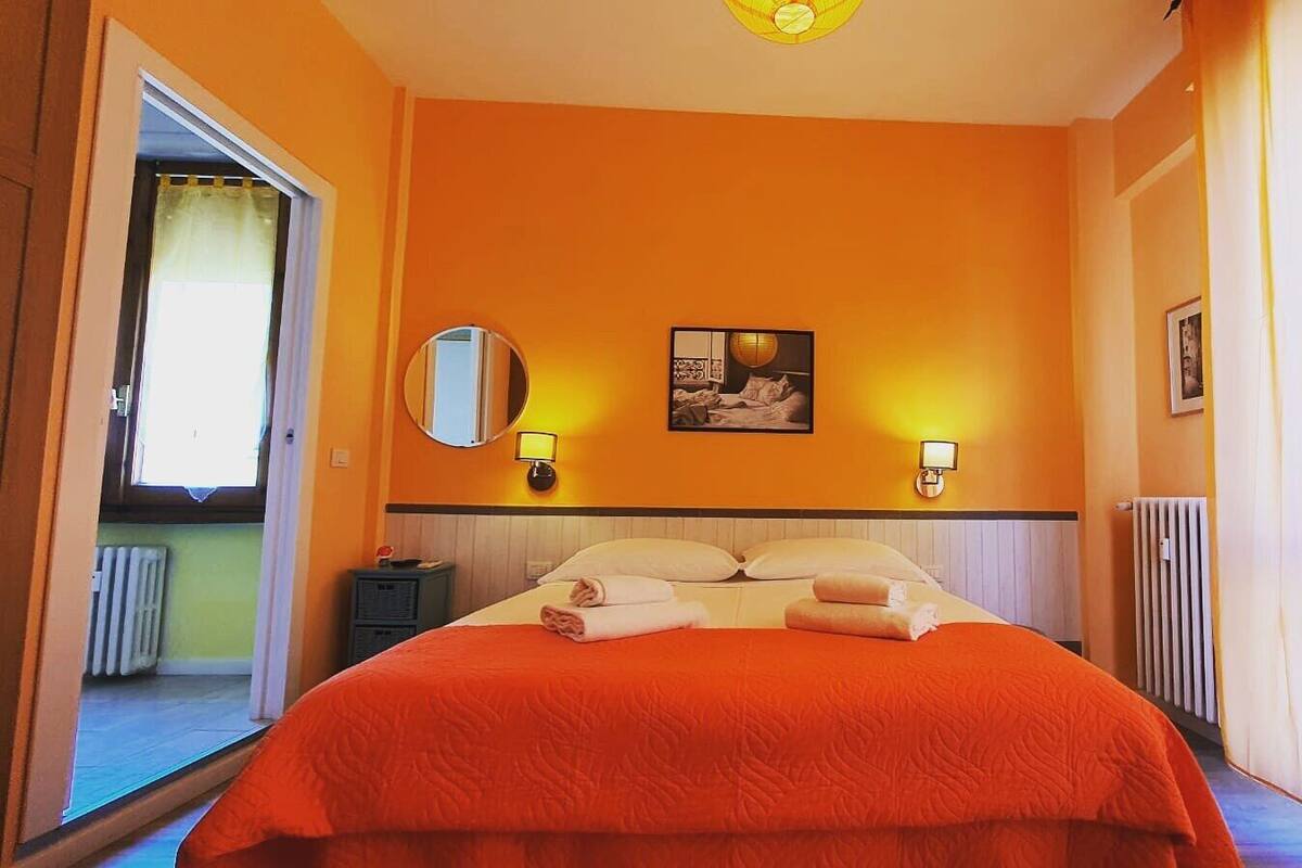 Ein Hotelzimmer mit einem großen Bett, zwei Wandlampen, einem runden Spiegel und einem Bild an der Wand.