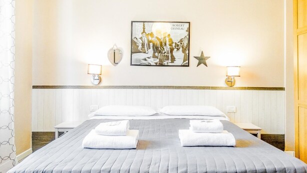 A hotel room with a bed, two bedside tables, a wall-mounted picture, two wall sconces, and a star decoration. - Il Giglio Guest House (Florence)